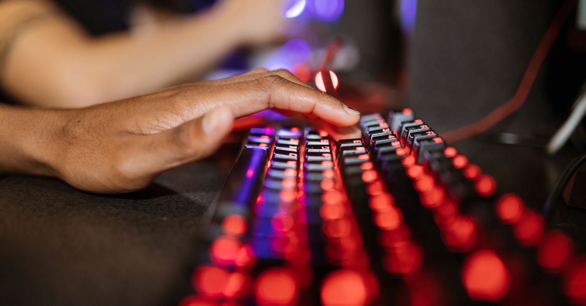 Primer plano de una mano sobre un teclado junto a una pantalla con gráficos financieros